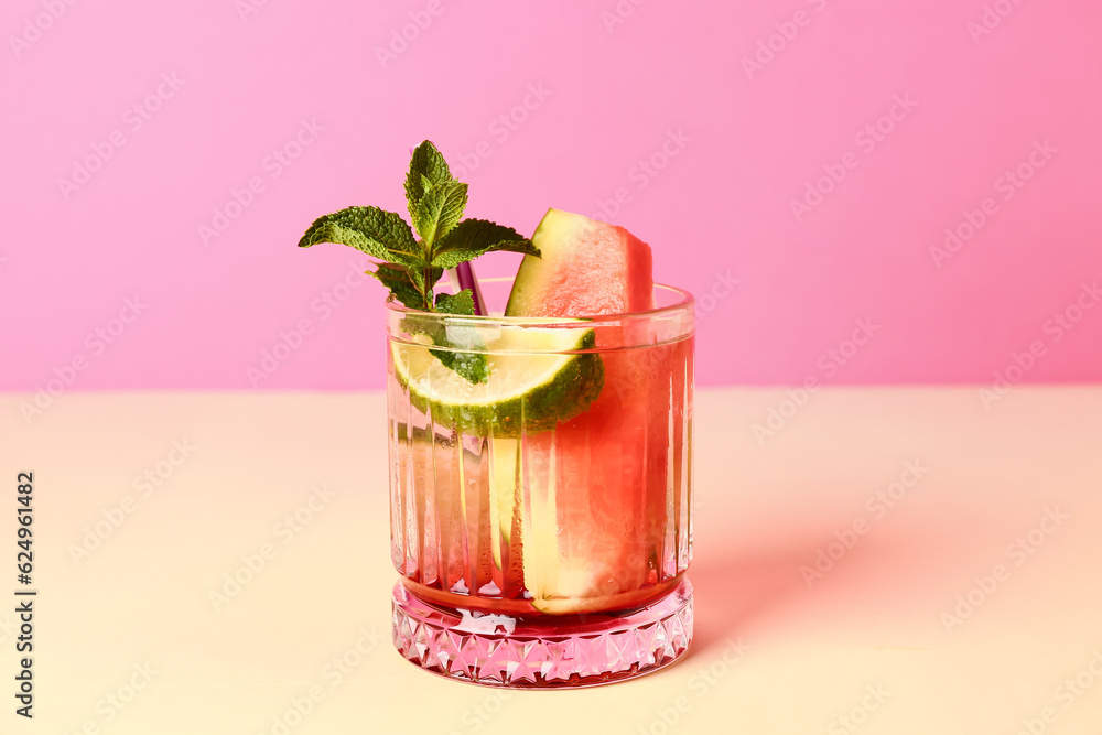 Glass of fresh watermelon lemonade with lime and mint on yellow table