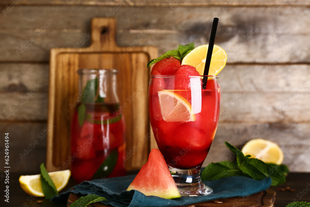 Glass and bottle of fresh watermelon lemonade and mint on wooden background