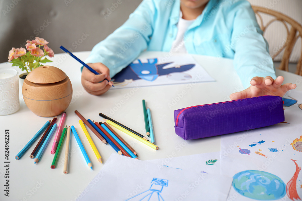 Little African-American boy with pencil case drawing at home, closeup