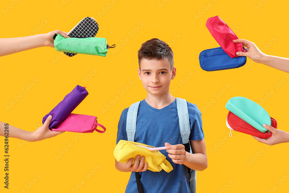 Little schoolboy and female hands with pencil cases on orange background