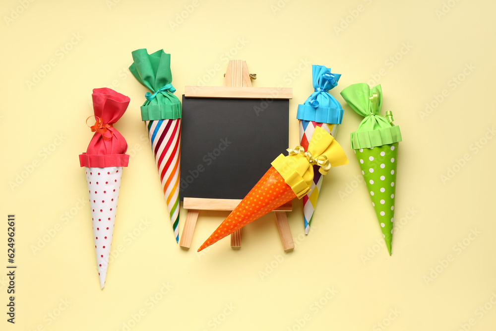 Colorful school cones and chalkboard on yellow background