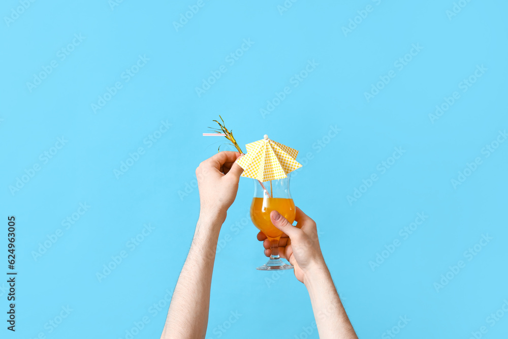 Male hands with glass of cocktail on blue background