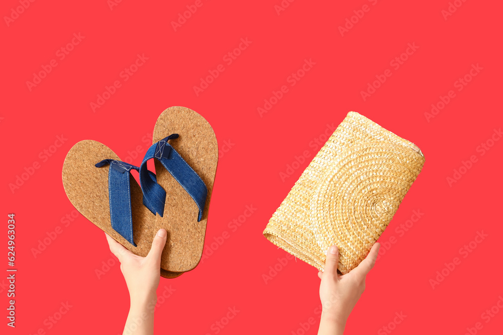 Female hands with wicker bag and flip flops on red background