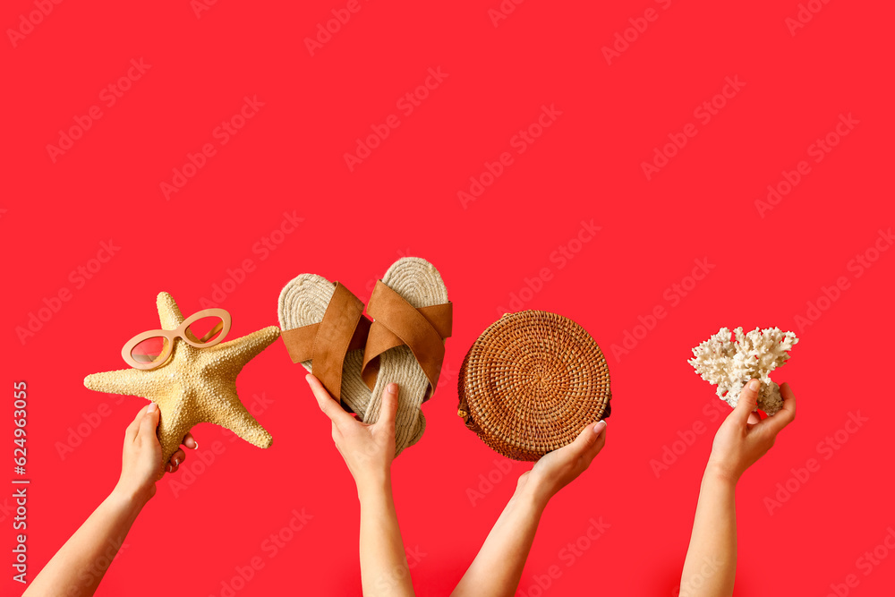 Many hands with beach accessories on red background