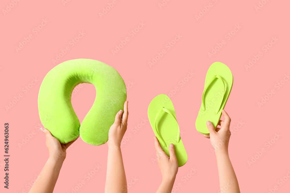 Many hands with travel cushion and flip flops on pink background