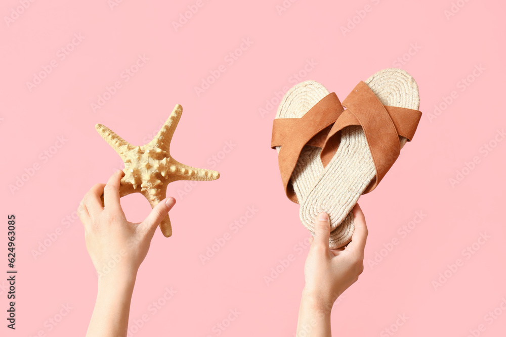 Female hands with flip flops and starfish on pink background