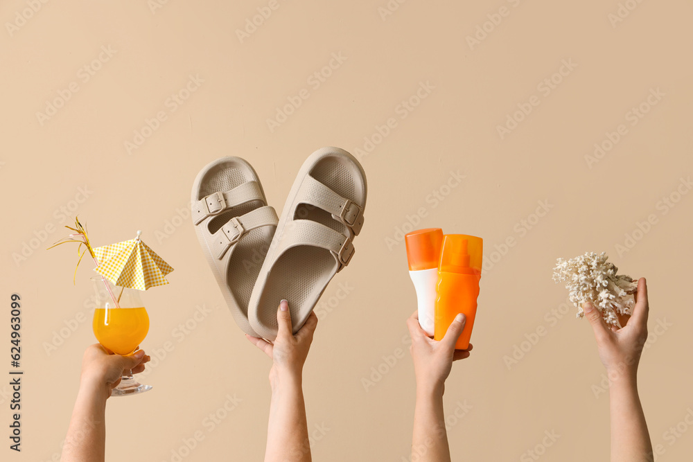 Female hands with beach accessories and cocktail on beige background