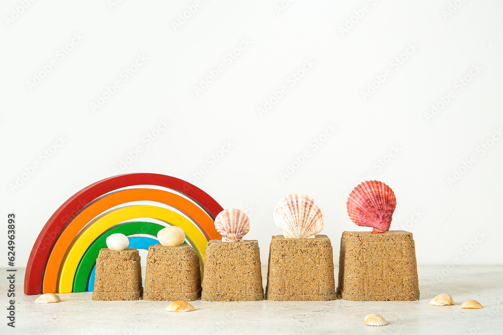 Castles made of sand with seashells and beach toys on white background