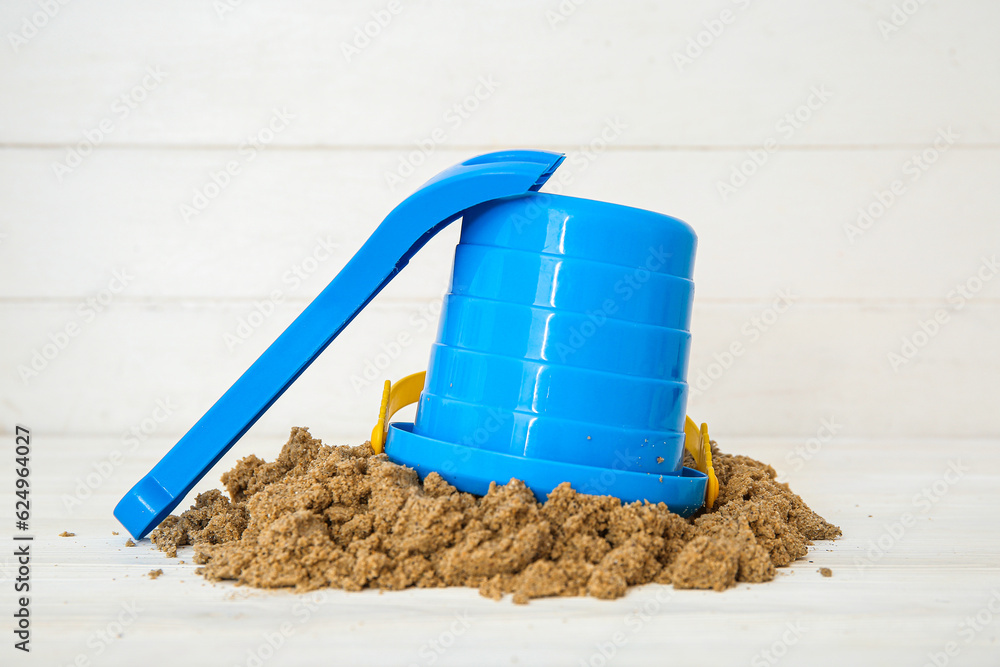 Sand pile with beach toys on white wooden background