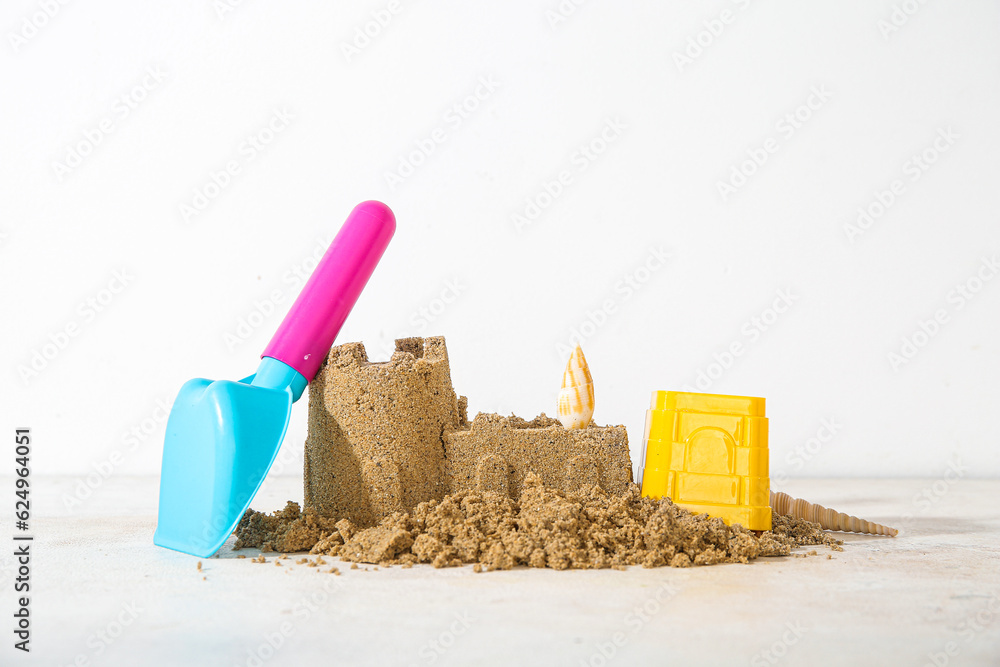 Castle made of sand with beach toys on white background