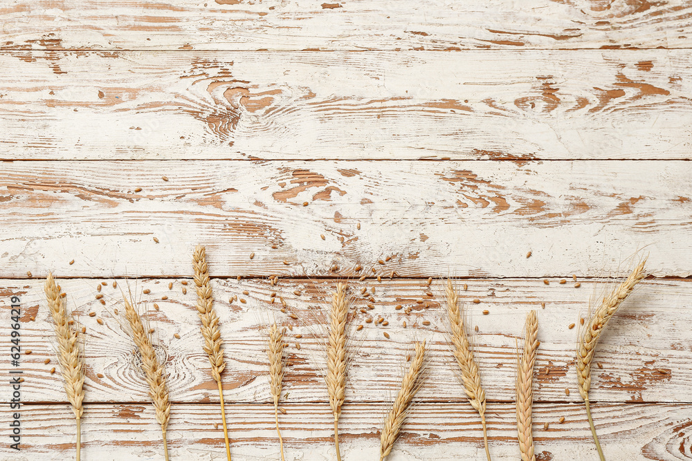 Wheat ears and grains on white wooden table