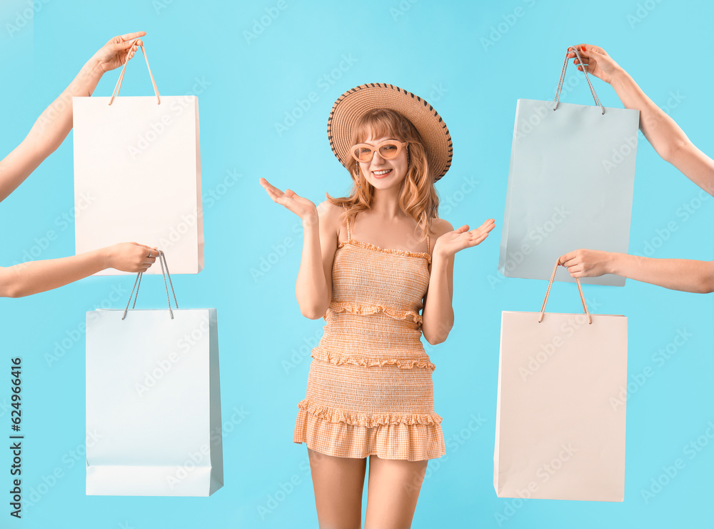 Beautiful happy young woman and hands with shopping bags on blue background