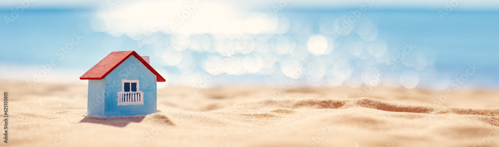 Miniature model of a house standing on the sand on the seacoast.