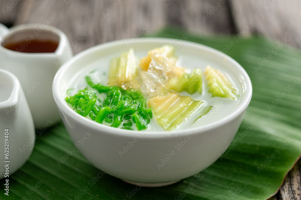 Close up of Lod Chong Thai dessert topped with coconut milk and pandan leaf followed by green banana