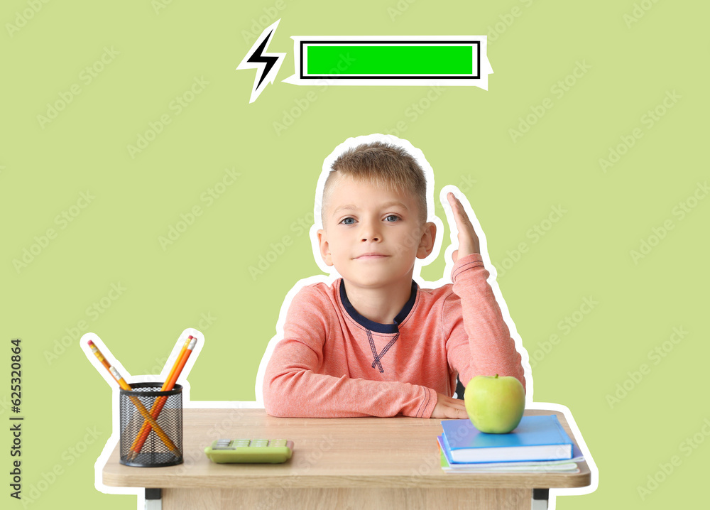 Smart little boy with raised hand for answer sitting at desk against green background