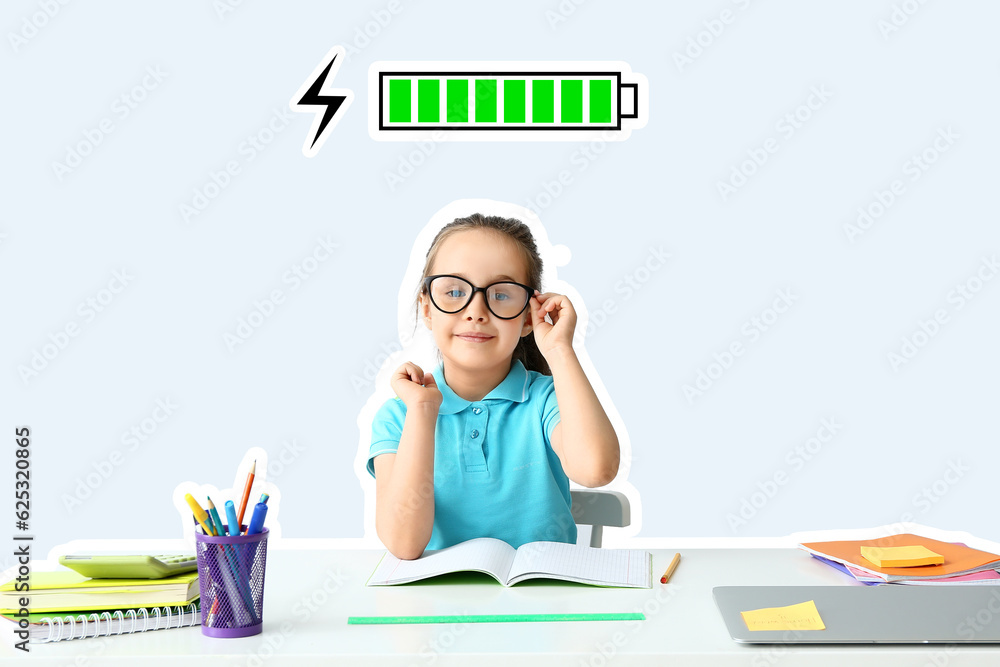 Smart little girl doing homework at table against light background