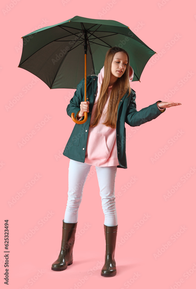 Teenage girl with green umbrella on pink background