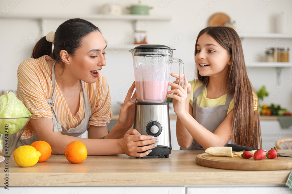 Little girl and her mother making smoothie with blender in kitchen