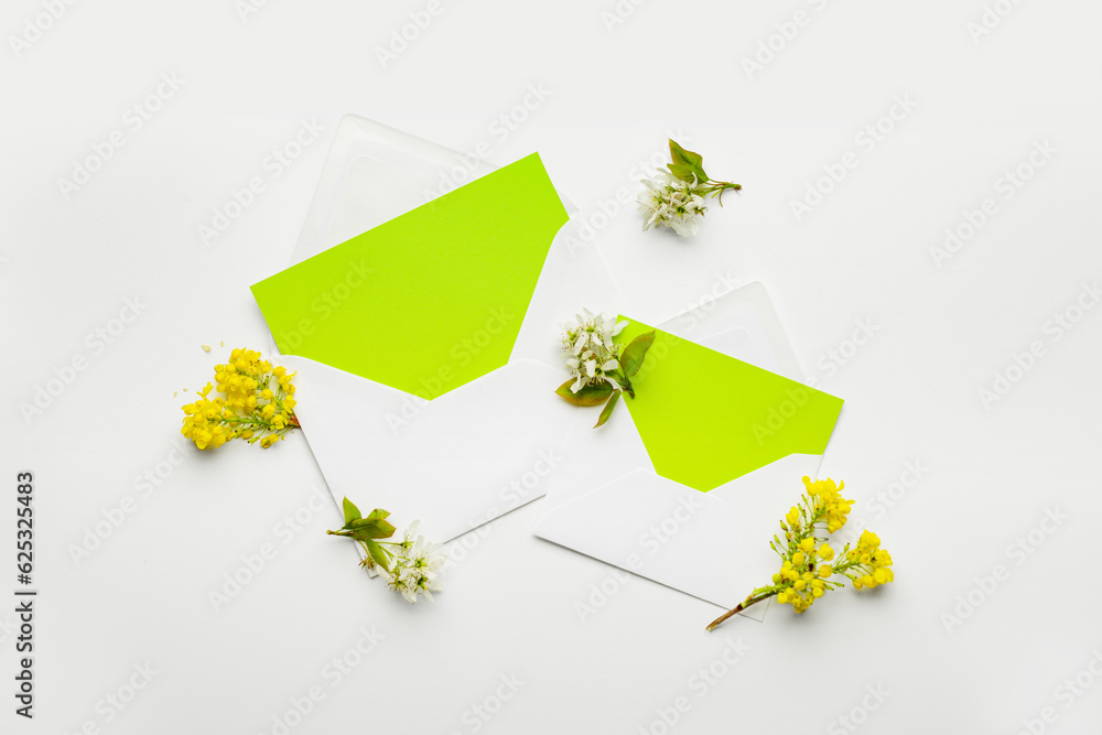 Composition with envelopes, blank cards and blooming plant branches on white background