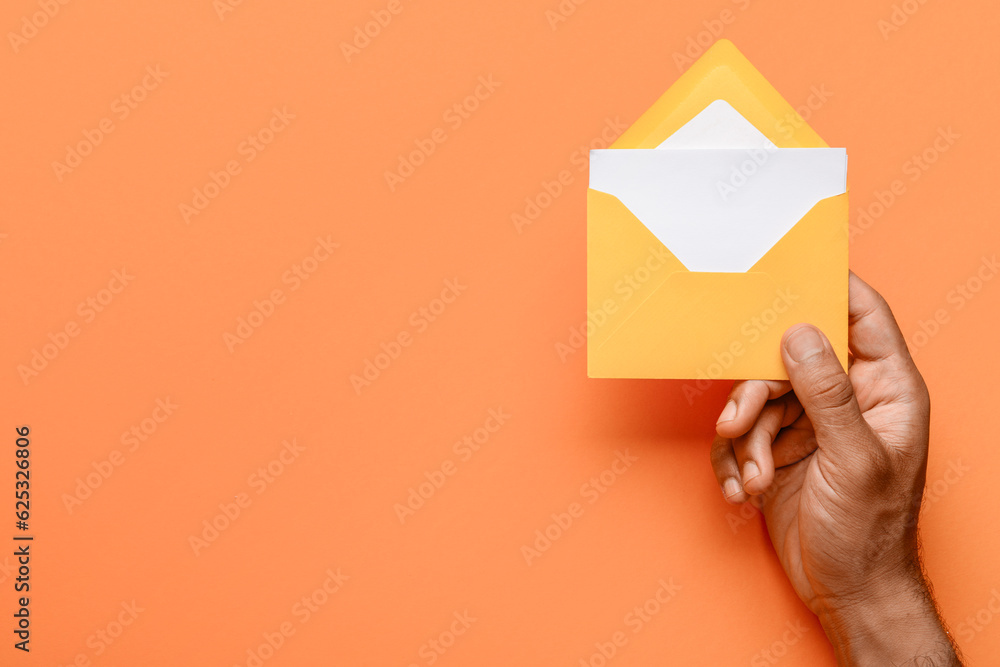 Male hand with envelope and blank card on color background