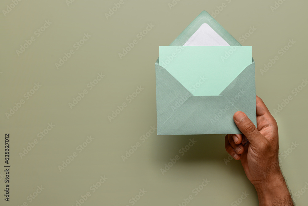 Male hand with envelope and blank card on color background, closeup