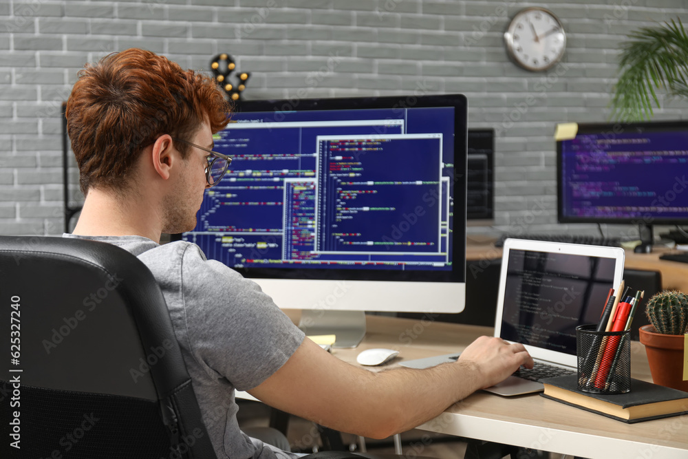 Male programmer working with laptop at table in office