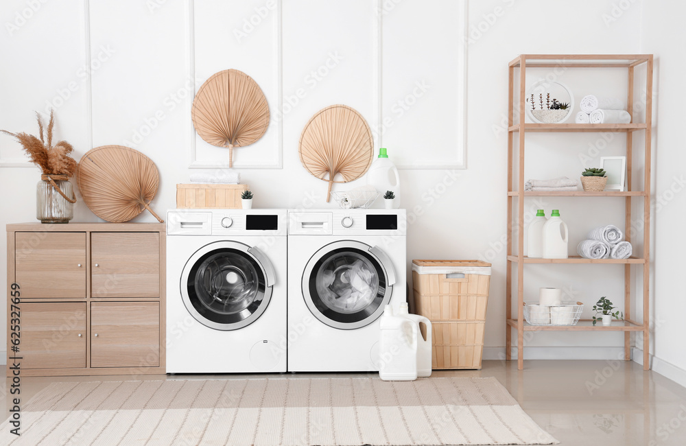 Interior of laundry room with washing machines, wooden cabinet and shelving unit