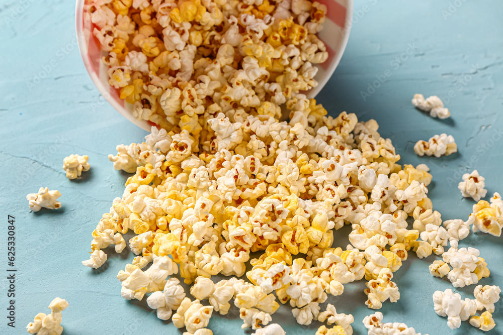 Bucket with tasty popcorn on blue background