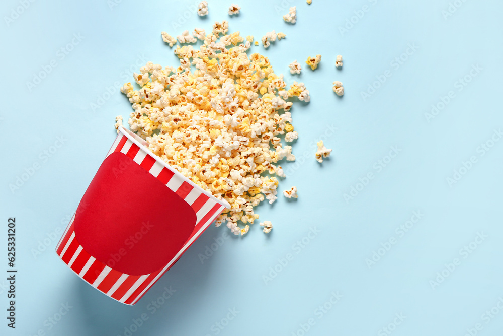 Bucket with tasty popcorn on blue background