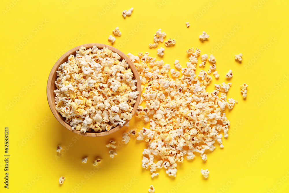 Bowl with tasty popcorn on yellow background