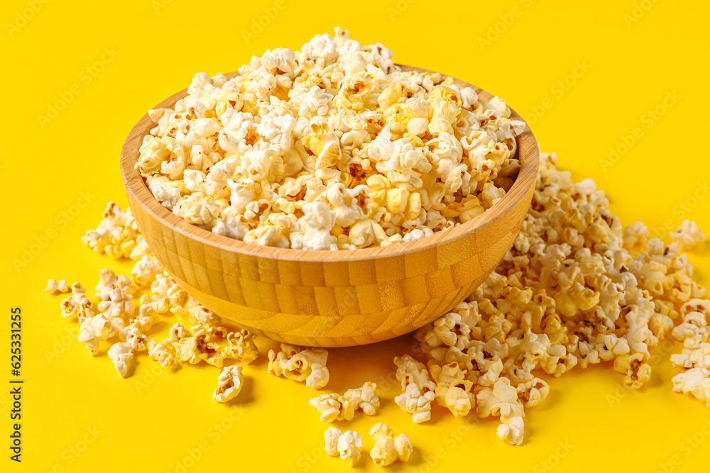 Bowl with tasty popcorn on yellow background