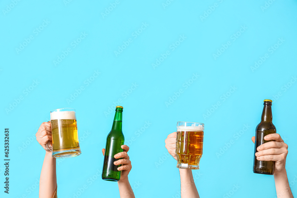 Many hands with bottles and mugs of cold beer on blue background