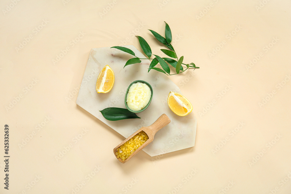 Board with bowl of lemon body scrub and sea salt on beige background