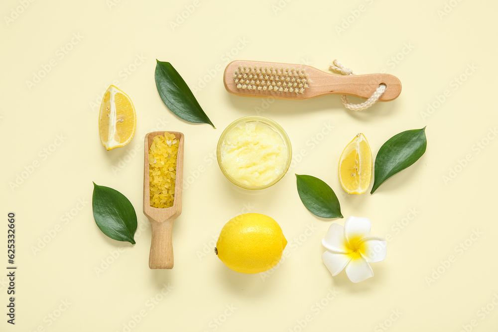 Bowl of lemon body scrub with massage brush and sea salt on pale yellow background