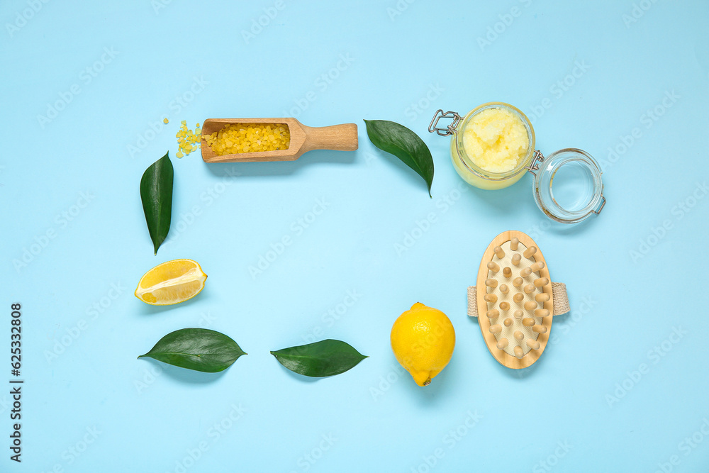 Frame made of lemon body scrub with massage brush and sea salt on blue background