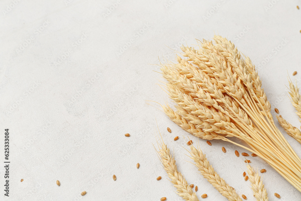 Bundle of wheat ears and grains on white table