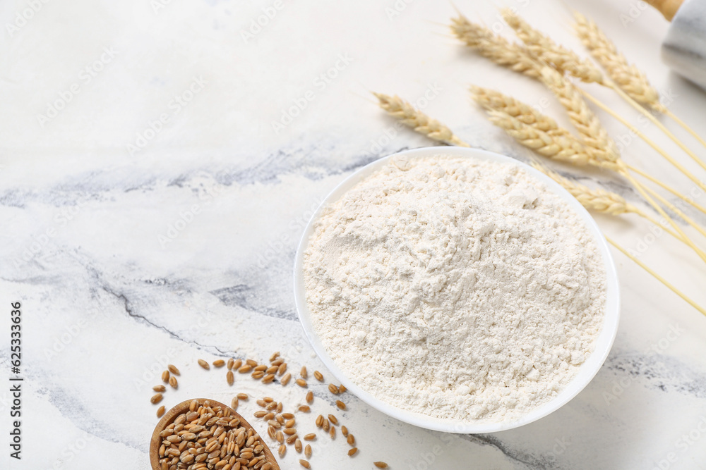 Bowl with wheat flour on white table, closeup