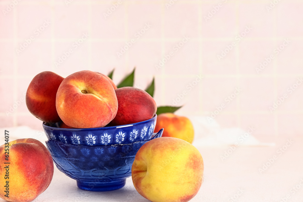 Bowl with sweet peaches on white table