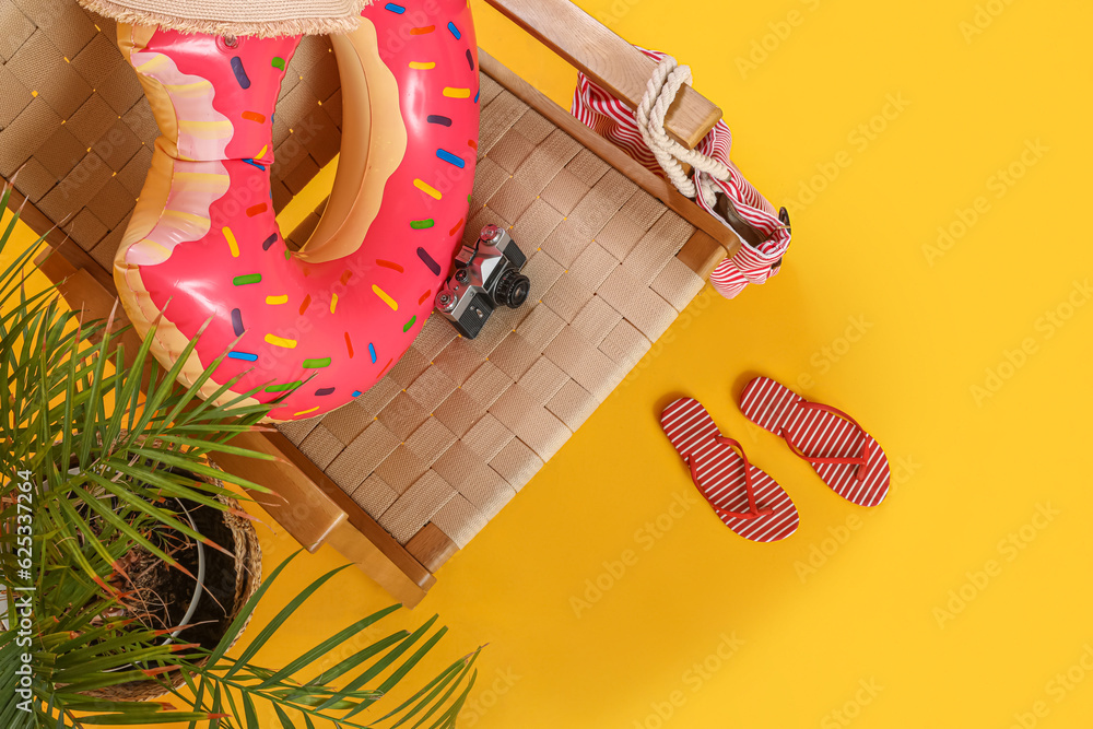 Chair with beach accessories, photo camera and palm tree on color background