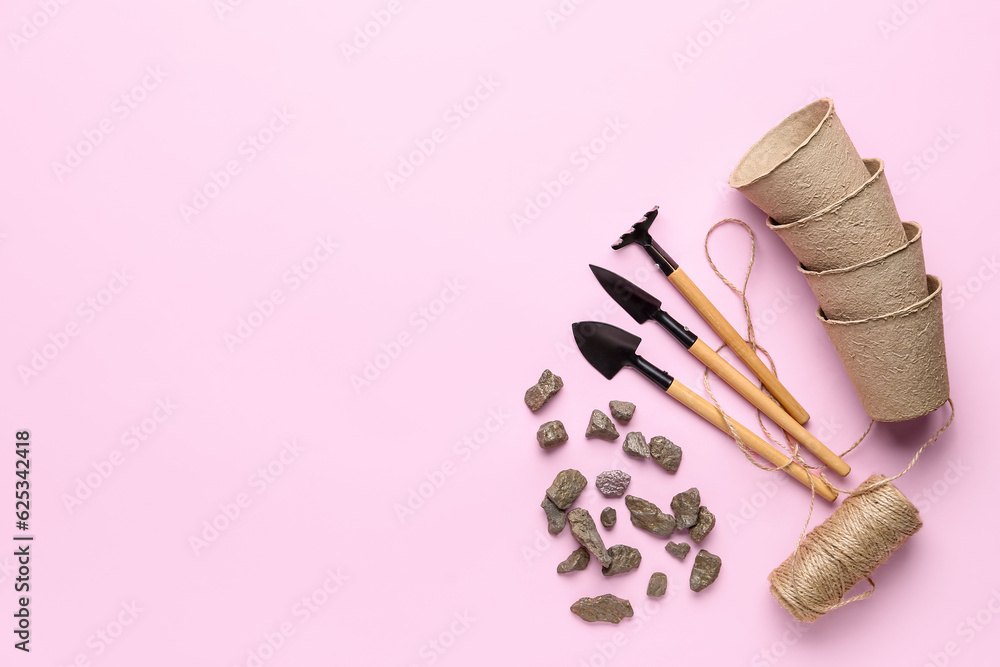 Gardening tools, rocks and peat cups on pink background