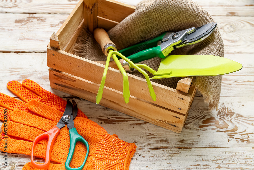 Gardening tools and gloves on white wooden background