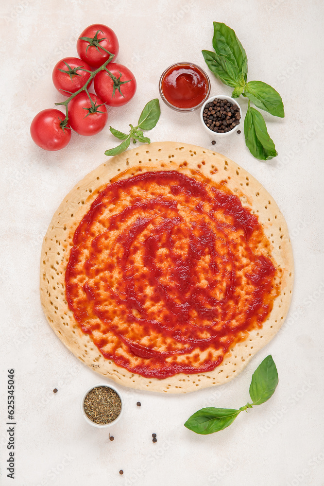 Pizza crust with tomato sauce and ingredients on light background