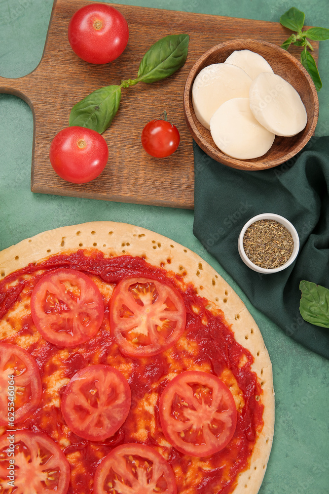 Tasty pizza and ingredients on green background