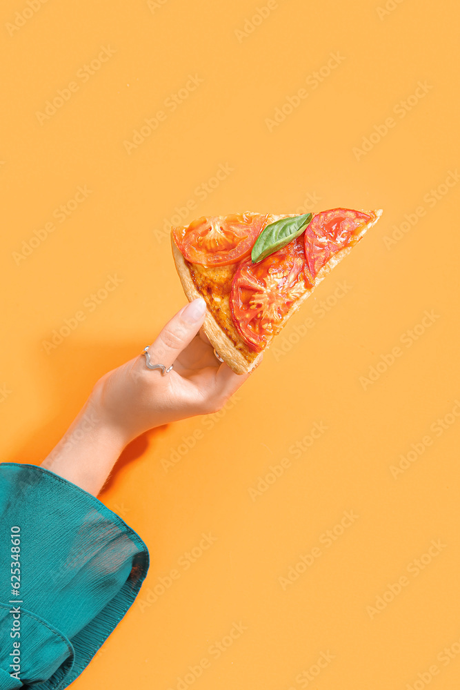 Woman holding slice of tasty pizza on orange background