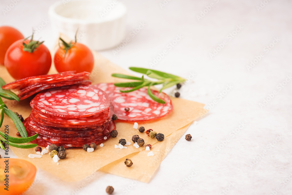 Slices of tasty salami on light background