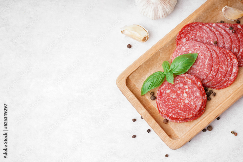 Slices of tasty salami on light background