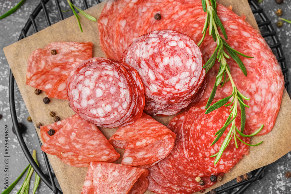 Grid with slices of tasty salami on grey background