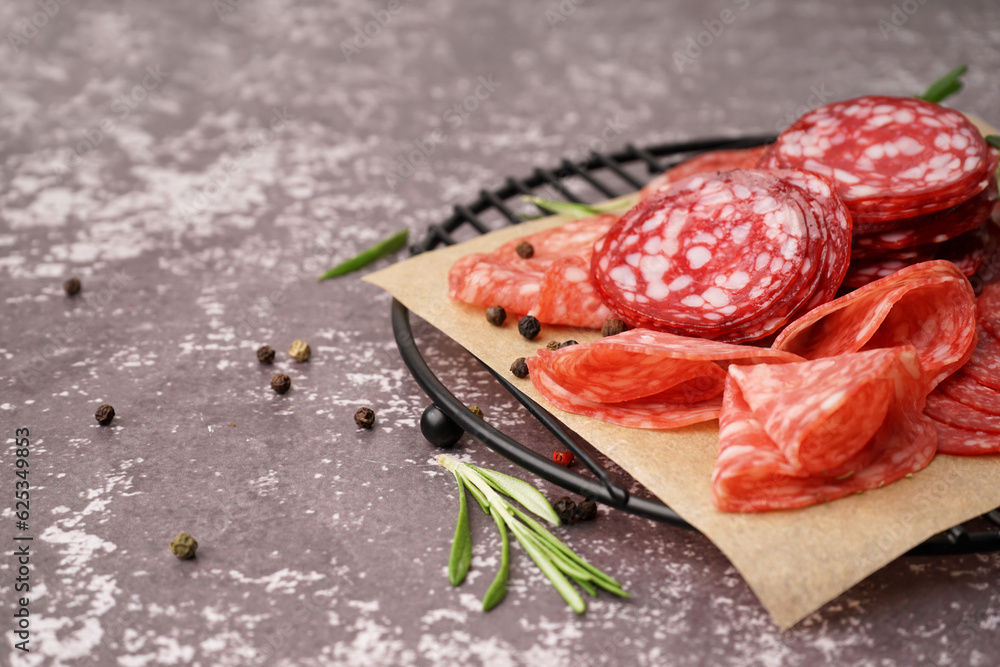 Grid with slices of tasty salami on grey background