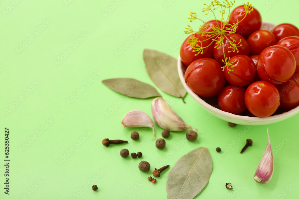 Bowl with canned tomatoes, peppercorn and garlic on green background