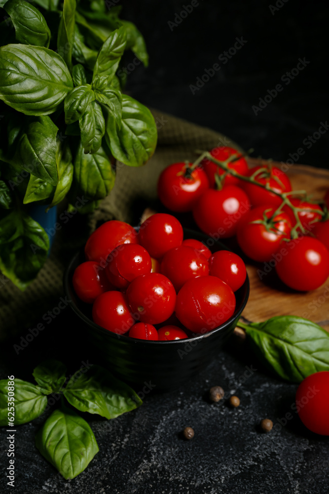 Bowl with canned tomatoes and basil on black background